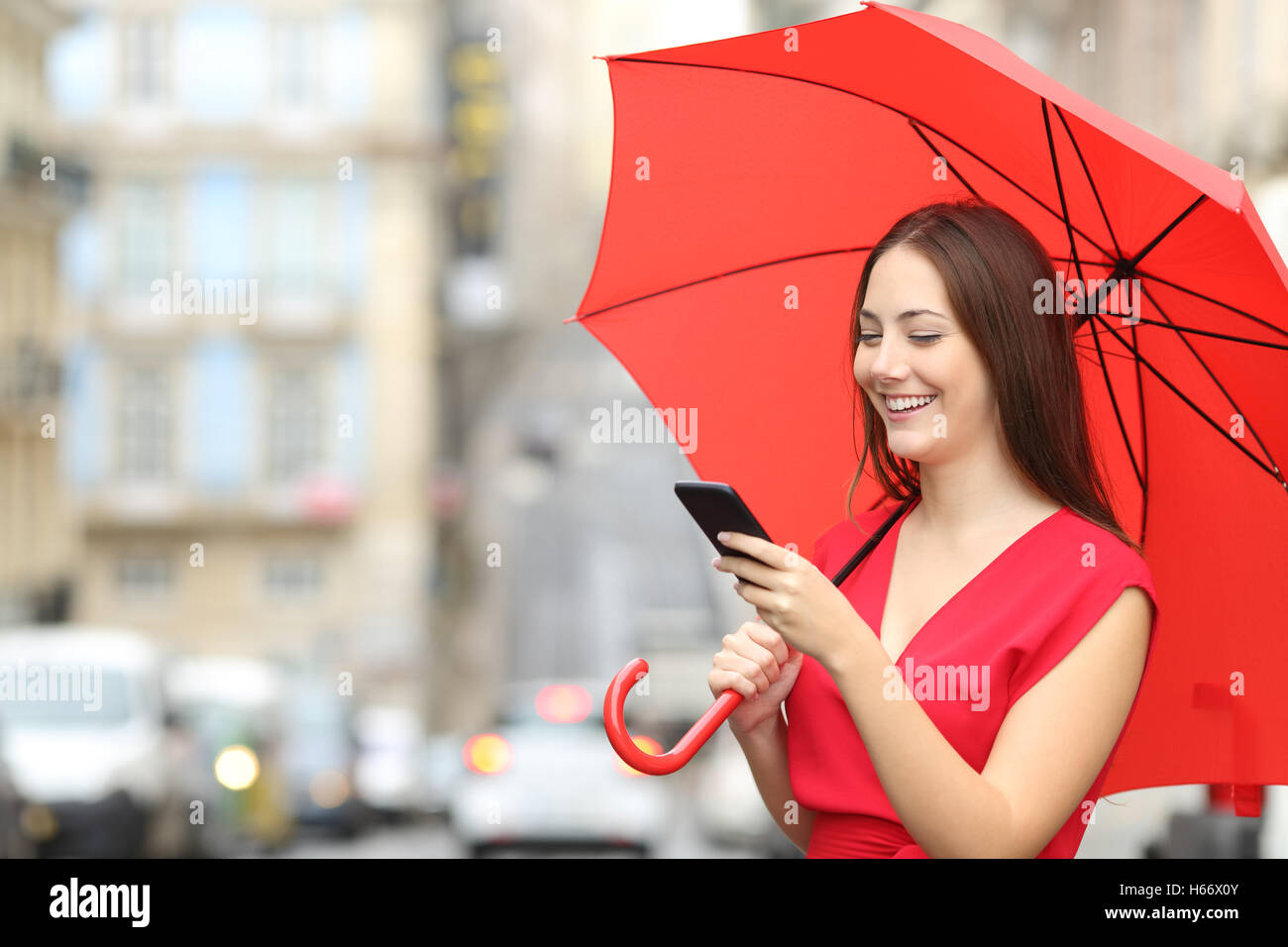 retrato-de-una-mujer-alegre-y-vistiendo-una-blusa-roja-de-texto-en-un-telefono-inteligente-bajo-un-paraguas-en-un-dia-de-lluvia-h66x0y.jpg
